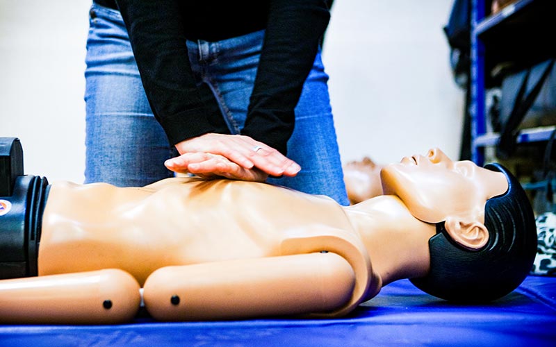 Eine Frau übt im Ersthelfer-Kurs an einem Dummy die Herz-Druck-Massage